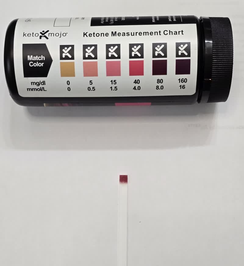Day 30 ketone strip next to the color chart reading deep in ketosis